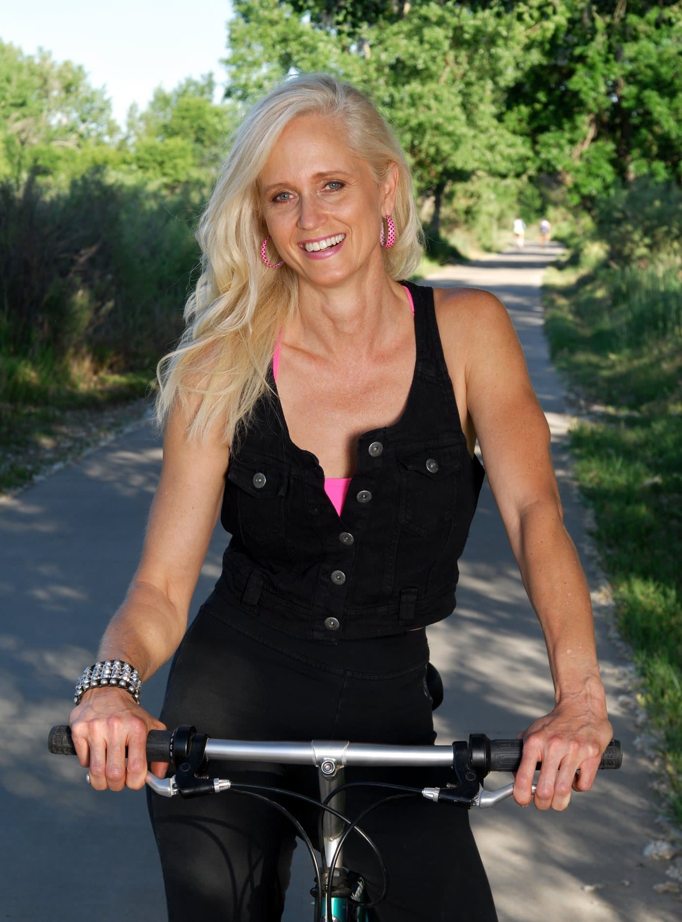 A woman riding a bicycle on a tree-lined path