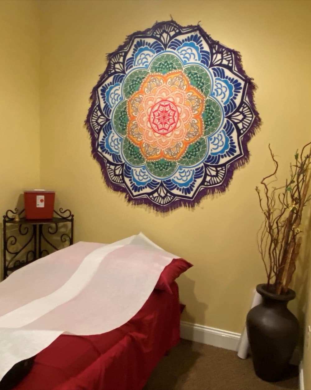 A treatment room with a mandala wall hanging above the table